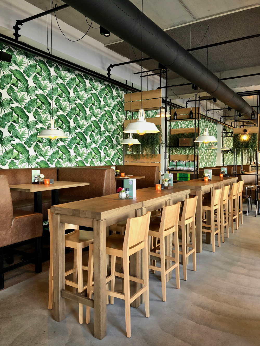 Hoge tafels en een jungle behang in het restaurant